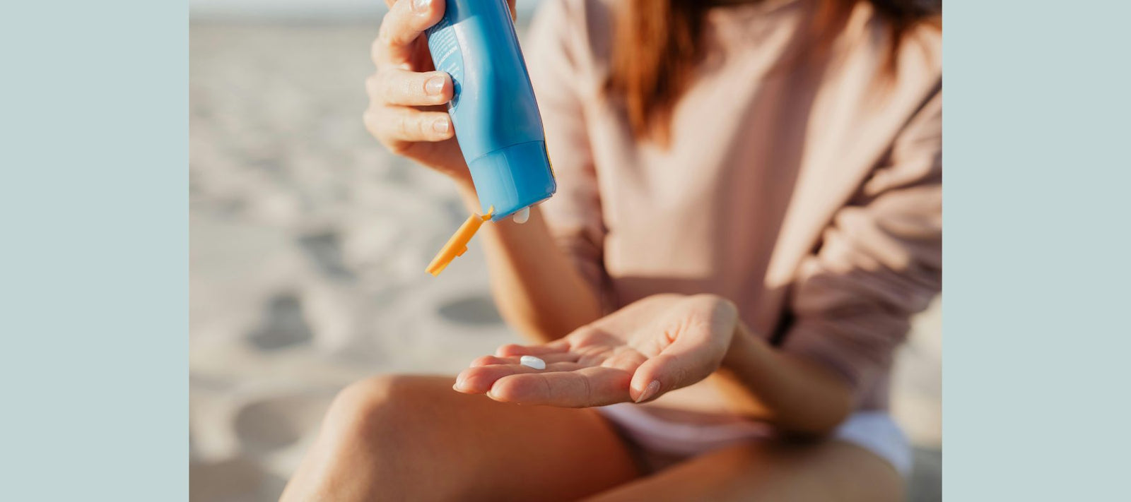woman at beach with sunscreen bottle