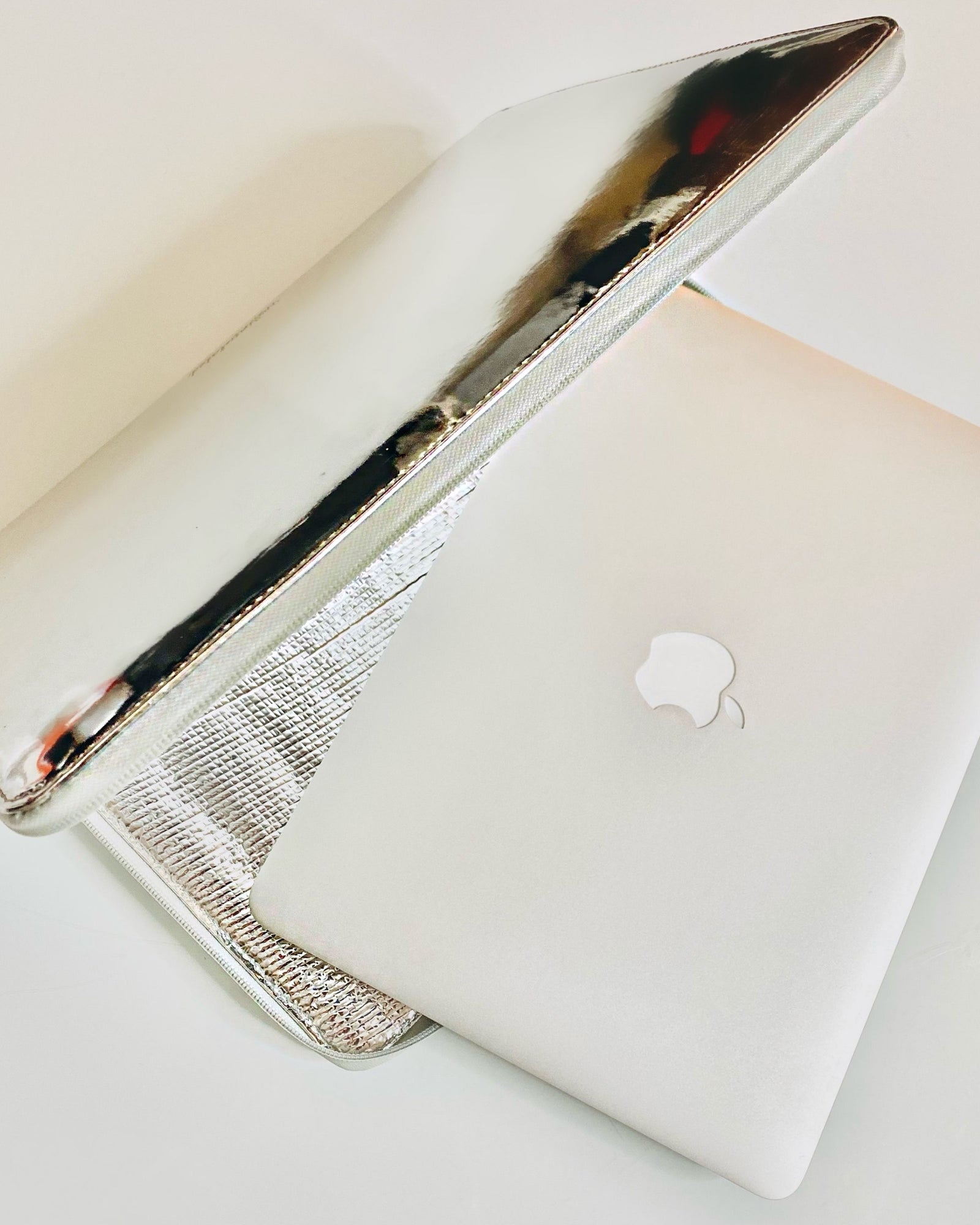 Silver metallic laptop sleeve protecting 14" MacBook Pro laptop.